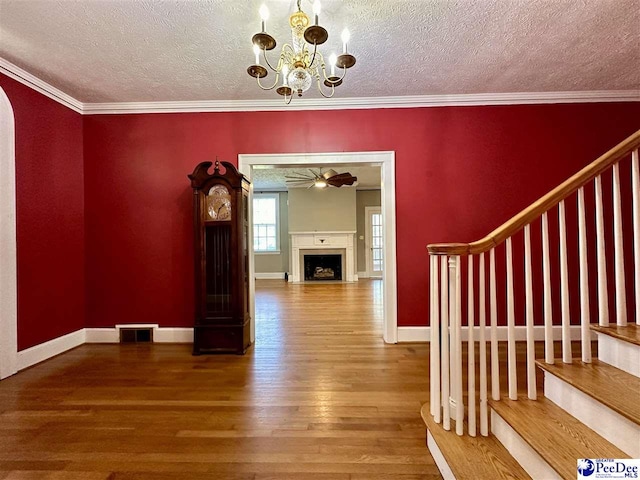 interior space featuring crown molding, hardwood / wood-style flooring, ceiling fan with notable chandelier, and a textured ceiling