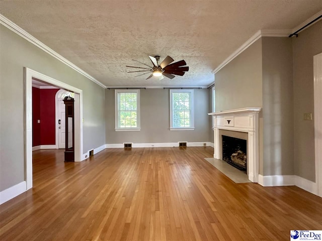 unfurnished living room with ceiling fan, wood-type flooring, ornamental molding, and a textured ceiling