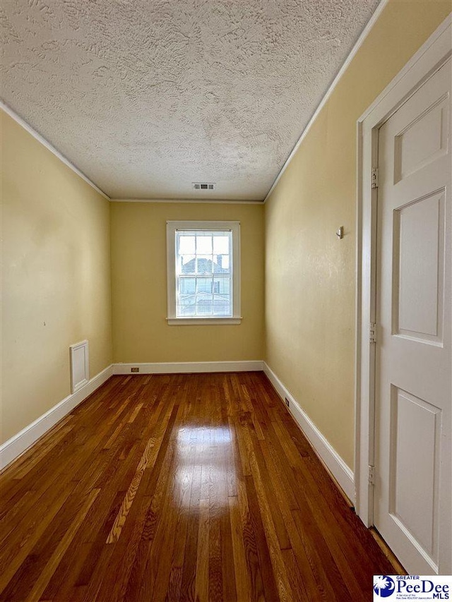 unfurnished room with crown molding, hardwood / wood-style flooring, and a textured ceiling