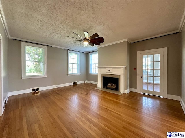 unfurnished living room featuring crown molding, wood-type flooring, a textured ceiling, ceiling fan, and a high end fireplace