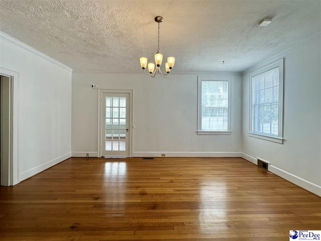 unfurnished room featuring hardwood / wood-style flooring, a wealth of natural light, and a chandelier