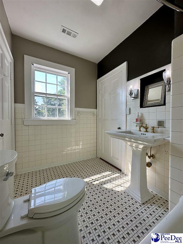 bathroom featuring tile walls, tile patterned flooring, and toilet