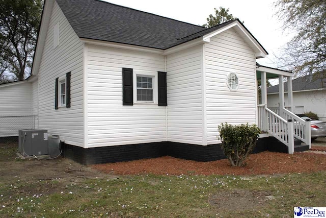 view of side of property featuring a shingled roof and central AC unit