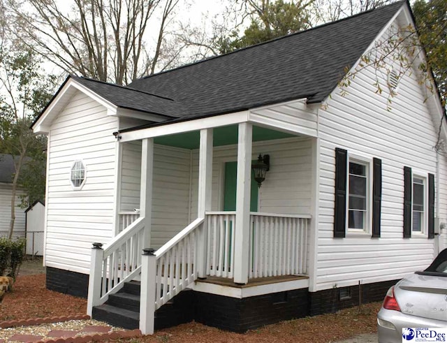 view of front of house with a shingled roof, crawl space, and a porch