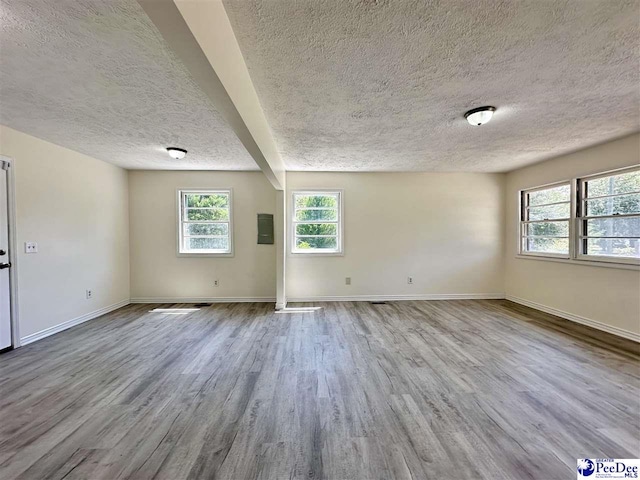 unfurnished room with a textured ceiling and light wood-type flooring