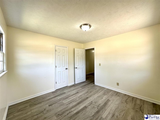 unfurnished bedroom featuring hardwood / wood-style flooring and a textured ceiling