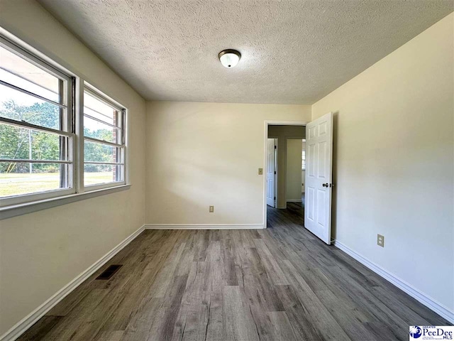 unfurnished room featuring dark hardwood / wood-style flooring and a textured ceiling