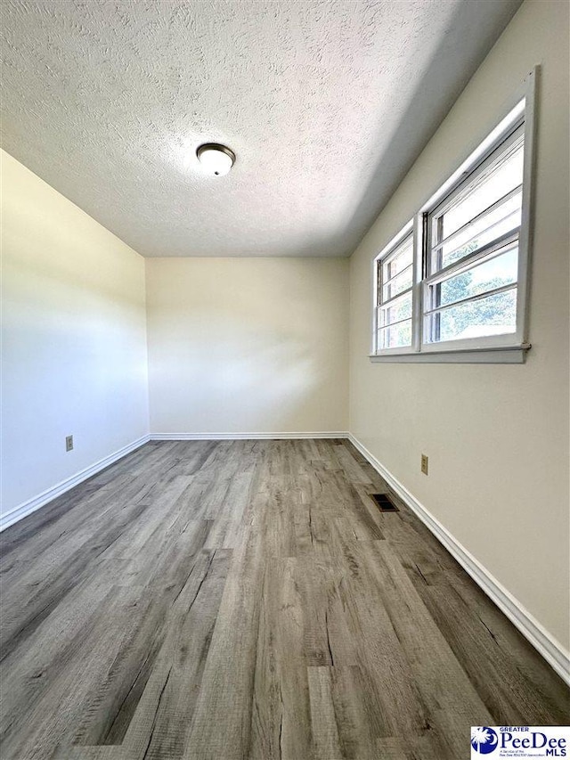 unfurnished room with wood-type flooring and a textured ceiling