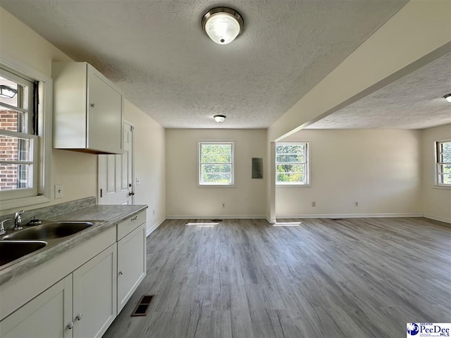 kitchen featuring sink, a textured ceiling, white cabinets, and light wood-type flooring