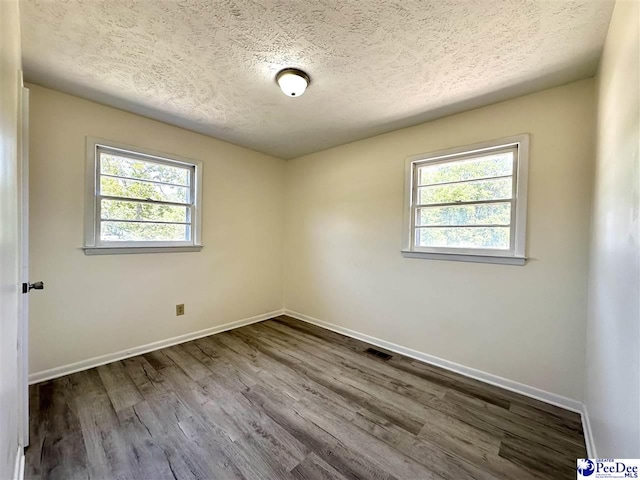 empty room with hardwood / wood-style floors and a textured ceiling