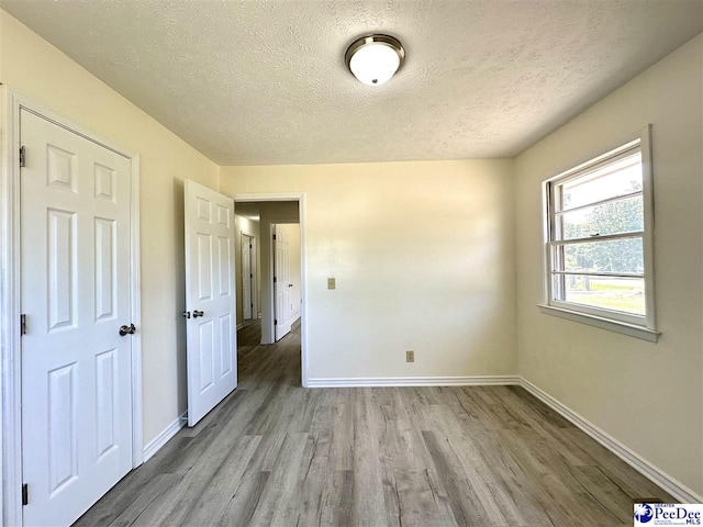 spare room featuring wood-type flooring and a textured ceiling