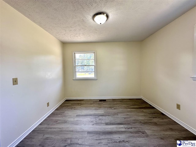 unfurnished room featuring dark hardwood / wood-style floors and a textured ceiling