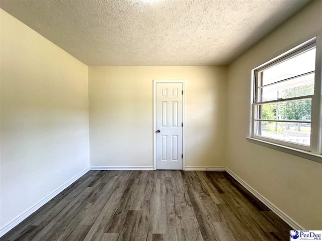 unfurnished room with dark wood-type flooring and a textured ceiling