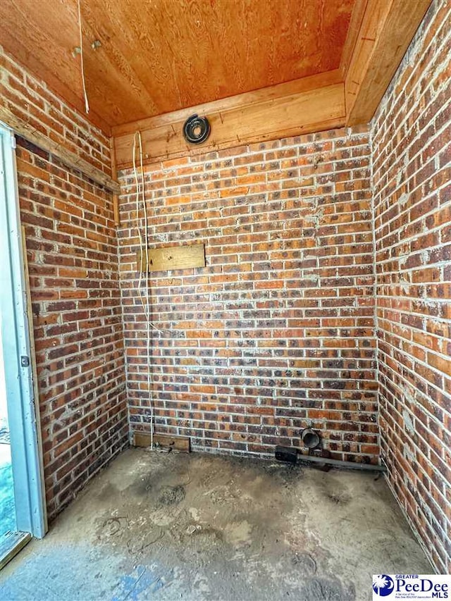 unfurnished room featuring concrete flooring and brick wall