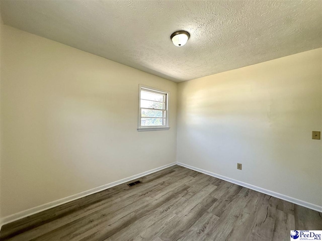 unfurnished room with wood-type flooring and a textured ceiling