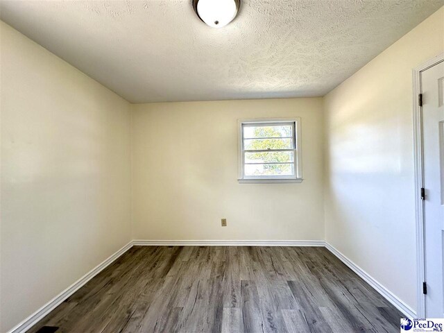 spare room featuring dark hardwood / wood-style flooring and a textured ceiling