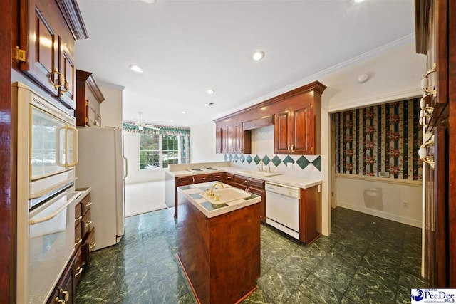 kitchen featuring a kitchen island, backsplash, ornamental molding, kitchen peninsula, and white appliances