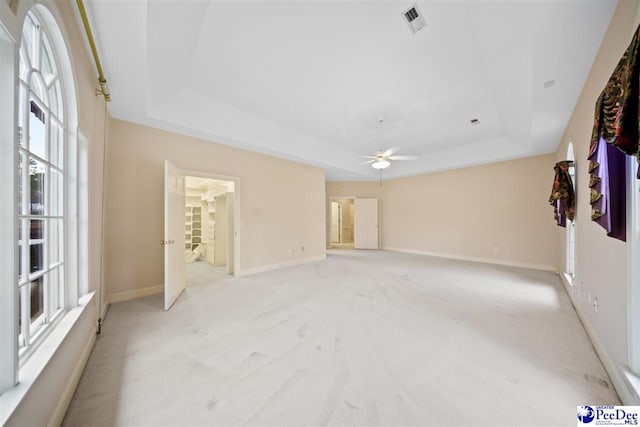 carpeted spare room with ceiling fan and a tray ceiling