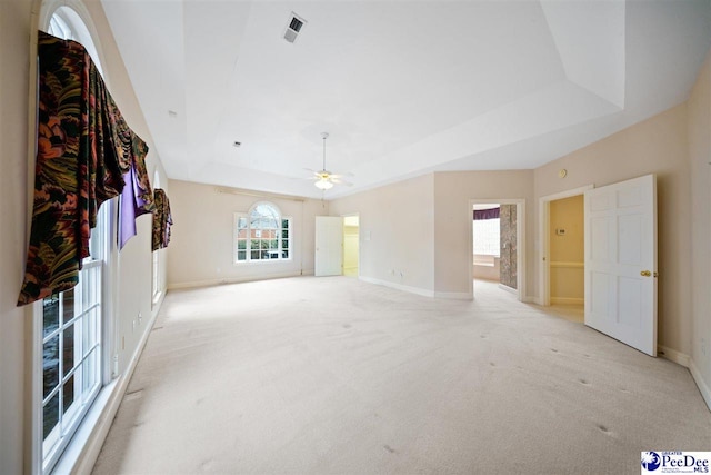 unfurnished living room with light carpet, a tray ceiling, and ceiling fan