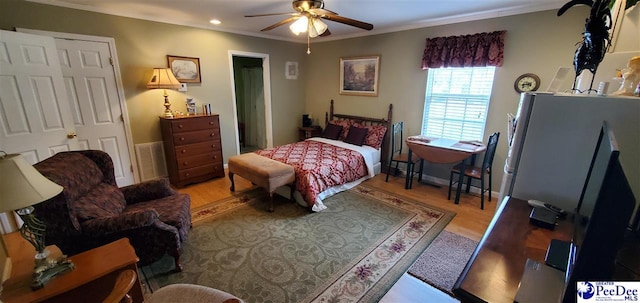 bedroom featuring light wood-style floors, visible vents, crown molding, and a ceiling fan