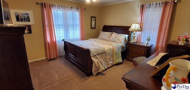 carpeted bedroom with ornamental molding and baseboards