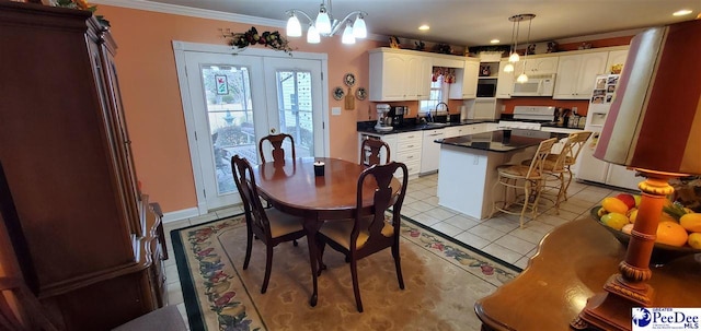 kitchen with white appliances, white cabinets, ornamental molding, a center island, and dark countertops