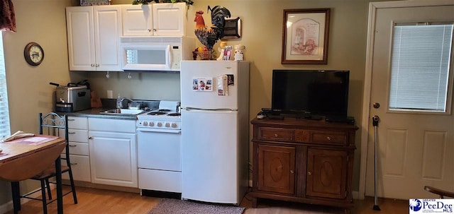 kitchen featuring white appliances, white cabinetry, light wood finished floors, and a sink