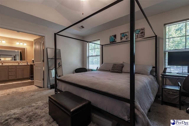 carpeted bedroom featuring lofted ceiling and ensuite bathroom