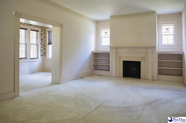 unfurnished living room with a tiled fireplace, ornamental molding, and light colored carpet