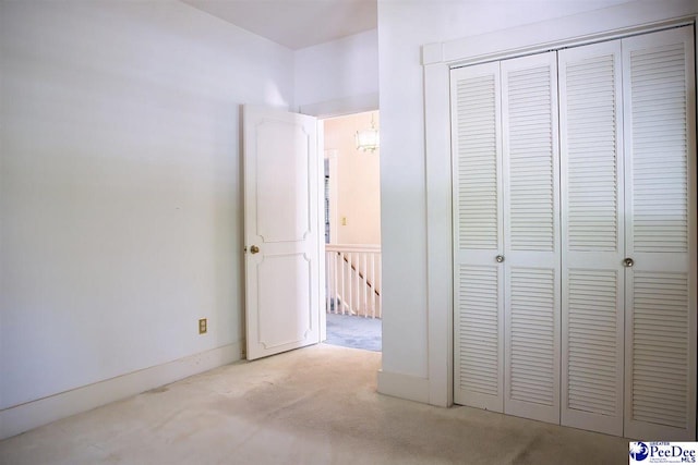 unfurnished bedroom featuring light carpet and a closet