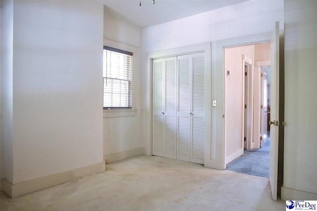 unfurnished bedroom with light colored carpet and a closet