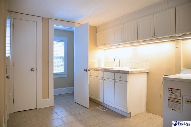 kitchen featuring sink, light tile patterned floors, and white cabinets