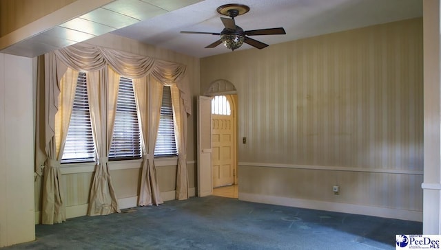 empty room with ceiling fan and dark carpet