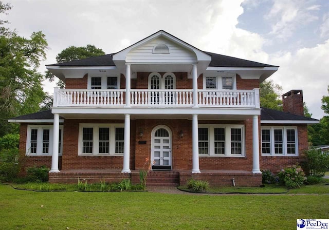 view of front of house featuring a balcony and a front lawn