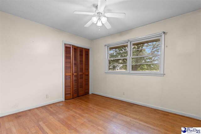 unfurnished bedroom with baseboards, a ceiling fan, wood finished floors, and a closet