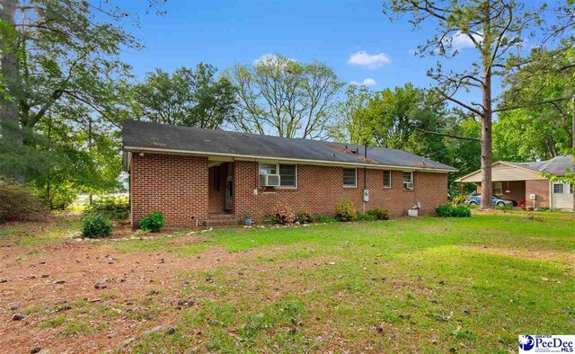 back of house with a lawn and brick siding