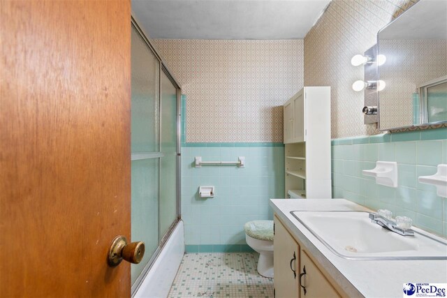 full bathroom featuring tile walls, tile patterned flooring, a wainscoted wall, bath / shower combo with glass door, and wallpapered walls