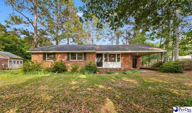 ranch-style house featuring brick siding, a front lawn, and a carport