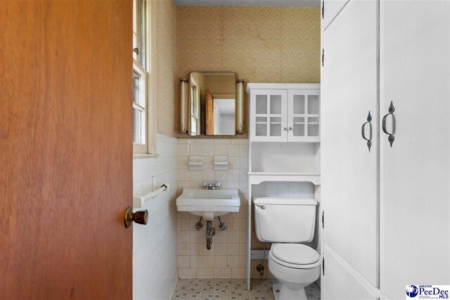 bathroom featuring toilet, tile walls, a sink, and tile patterned flooring