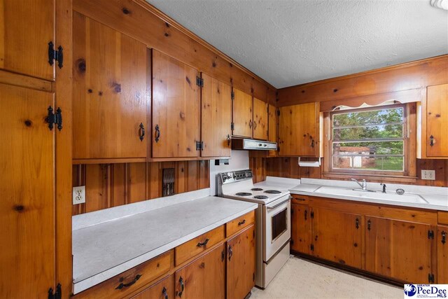 kitchen with under cabinet range hood, light countertops, brown cabinetry, and electric stove