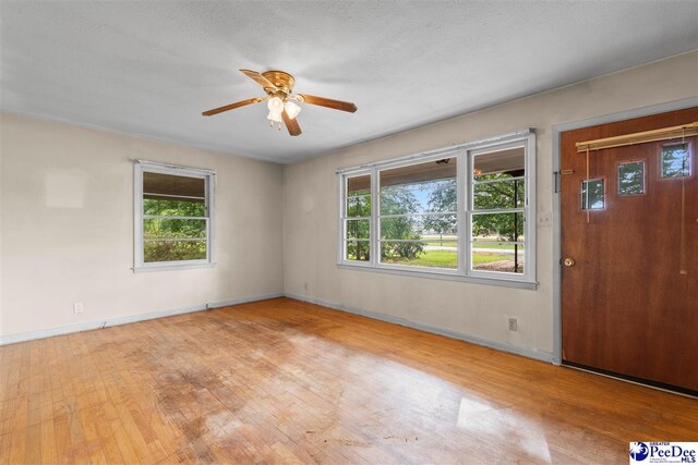 spare room with baseboards, plenty of natural light, a ceiling fan, and wood finished floors