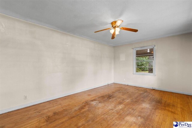 spare room featuring a ceiling fan, baseboards, and hardwood / wood-style flooring
