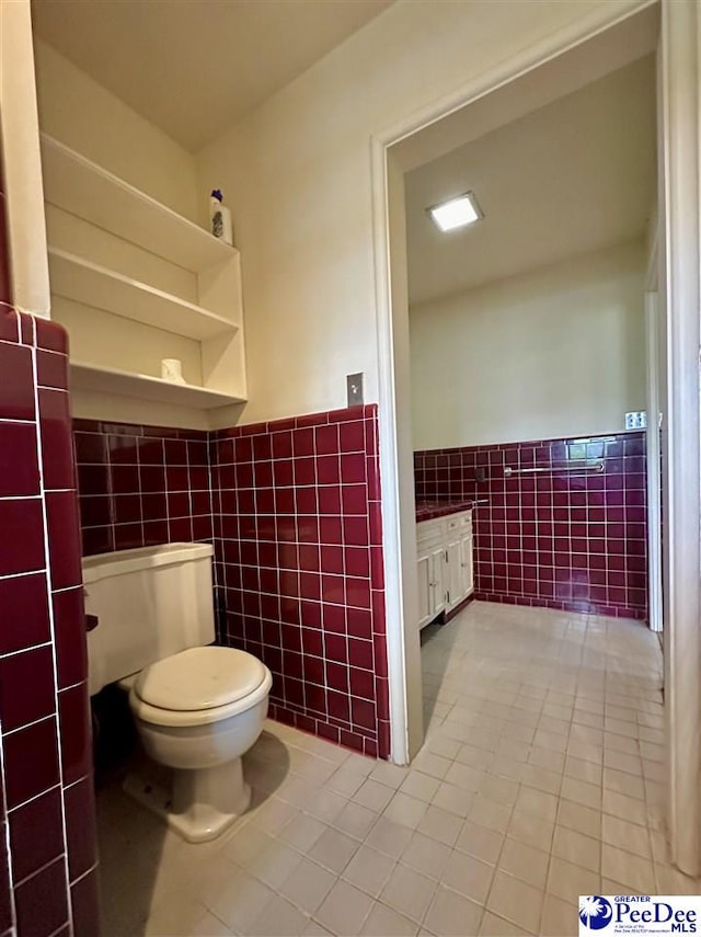 bathroom with tile patterned flooring, tile walls, and toilet