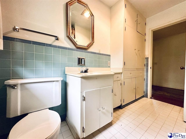 bathroom with tile patterned floors, vanity, toilet, and tile walls