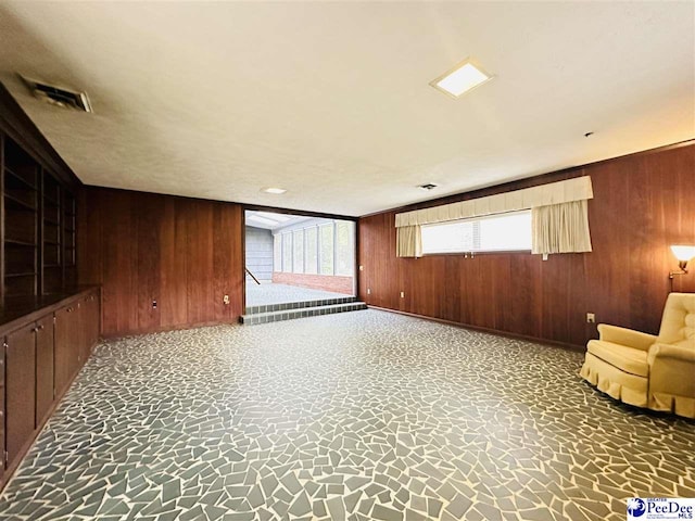 unfurnished living room with wood walls