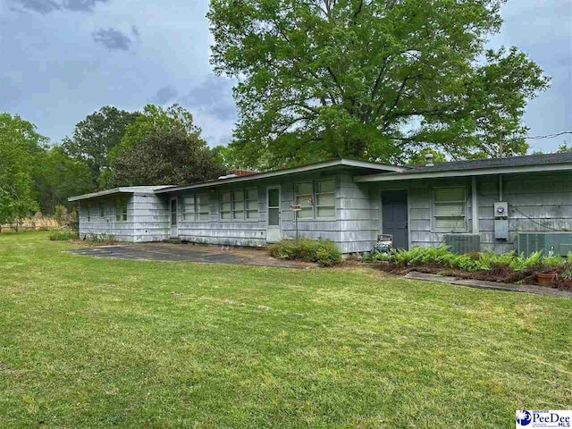 single story home with cooling unit and a front lawn