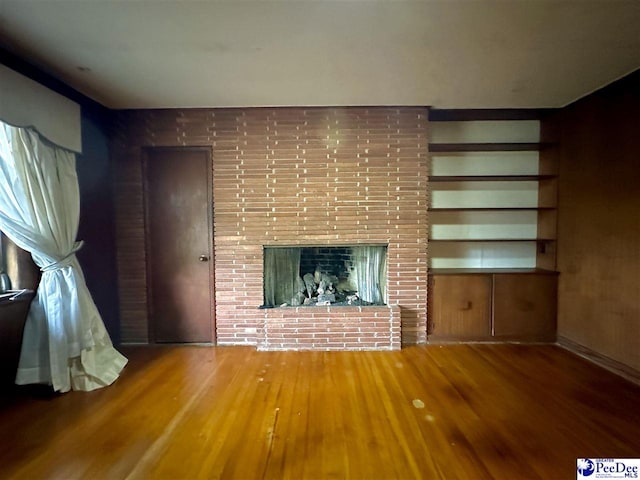 unfurnished living room featuring hardwood / wood-style floors, a fireplace, and built in features