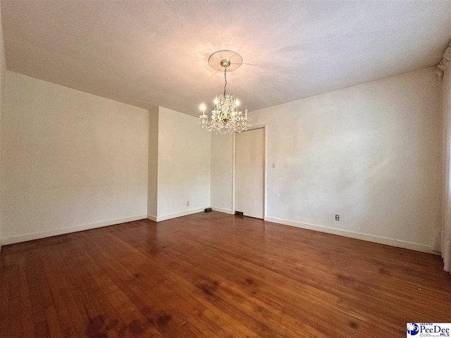 empty room featuring dark hardwood / wood-style floors and a chandelier