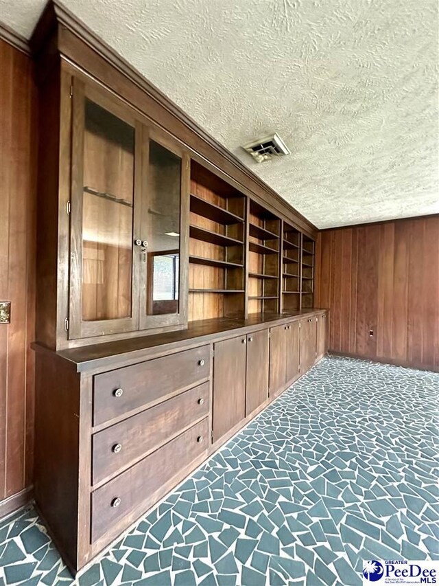 interior space featuring dark carpet, a textured ceiling, and wood walls