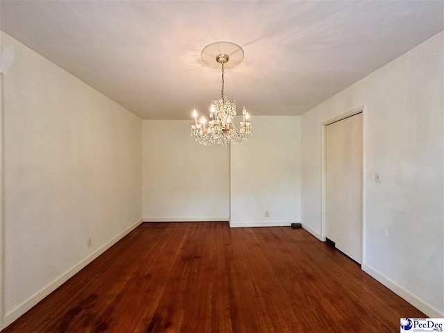 unfurnished dining area with dark wood-type flooring and a chandelier